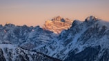 A serene sunrise over the snowy peaks of the Swiss Alps, casting golden light.