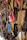 A variety of colorful, handcrafted leather shoes are hanging on display. The shoes come in a range of shades including red, blue, brown, yellow, and black, and feature intricate stitching and punched hole designs. They are neatly arranged in rows, creating a vibrant and artistic pattern.