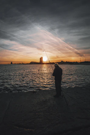 Sunset over a river with a lone angler silhouetted against the glowing sky.