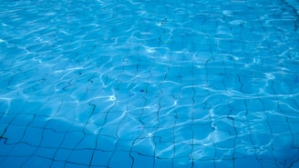 Clear water with gentle ripples reveals a tiled surface beneath, creating a serene and reflective appearance.