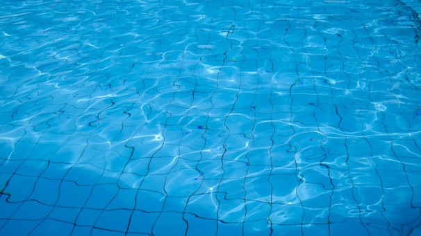 Clear water with gentle ripples reveals a tiled surface beneath, creating a serene and reflective appearance.