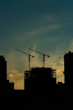Architectural blueprint overlay on a large urban construction project at sunset.