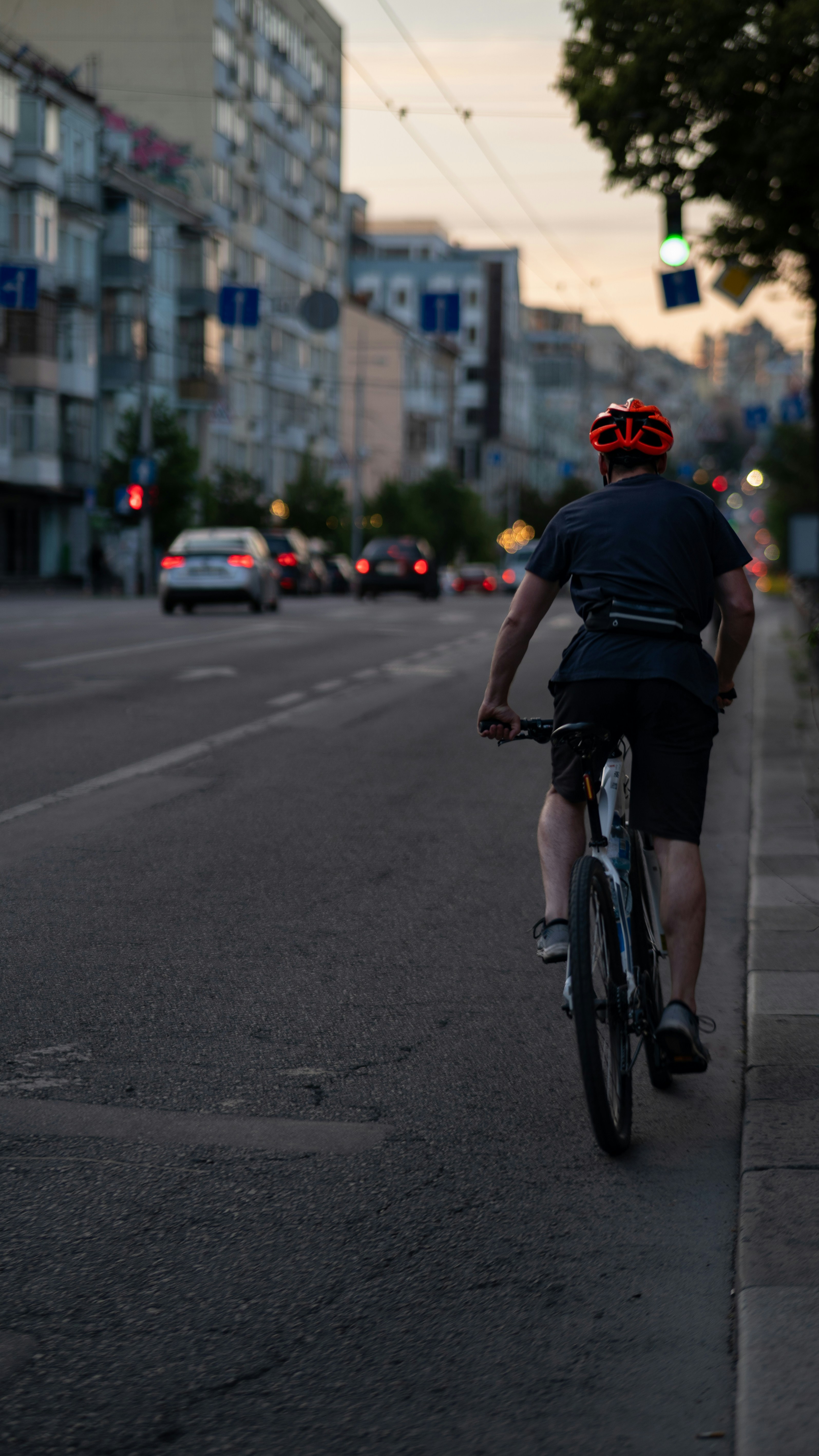 Un hombre montando en bicicleta por una calle junto a edificios altos