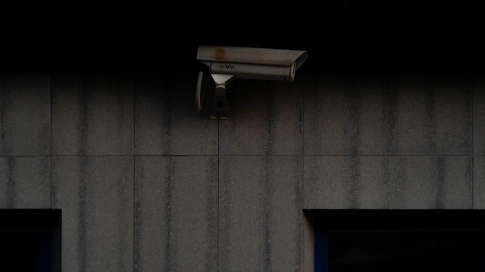 A sleek mexvision CCTV camera mounted discreetly on a modern home's exterior wall at dusk.