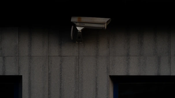 Close-up of a modern security camera mounted on a wall at dusk