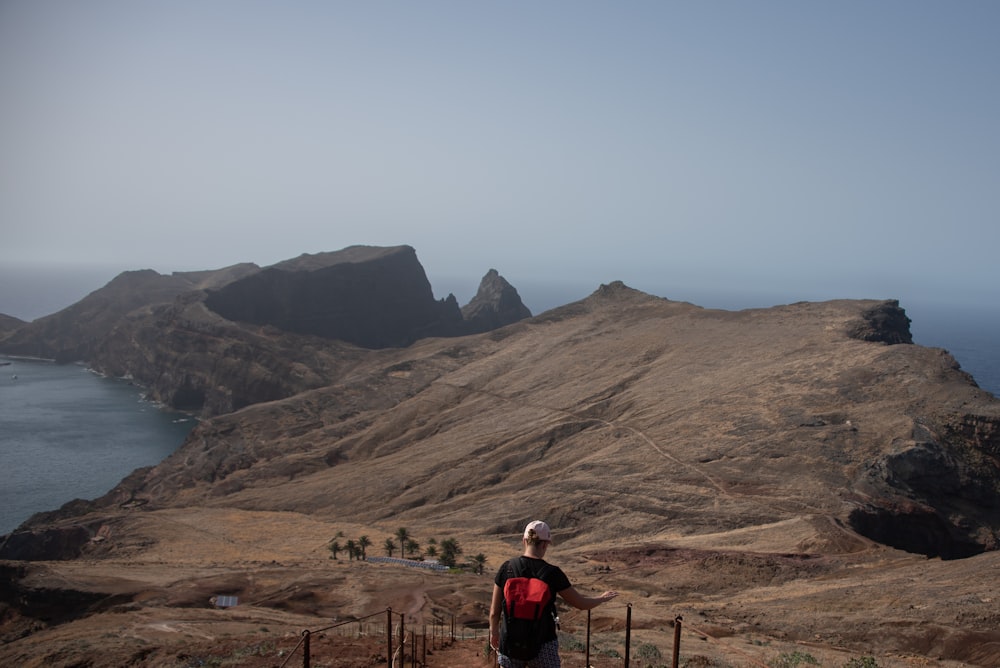 a man standing on top of a hill next to a body of water