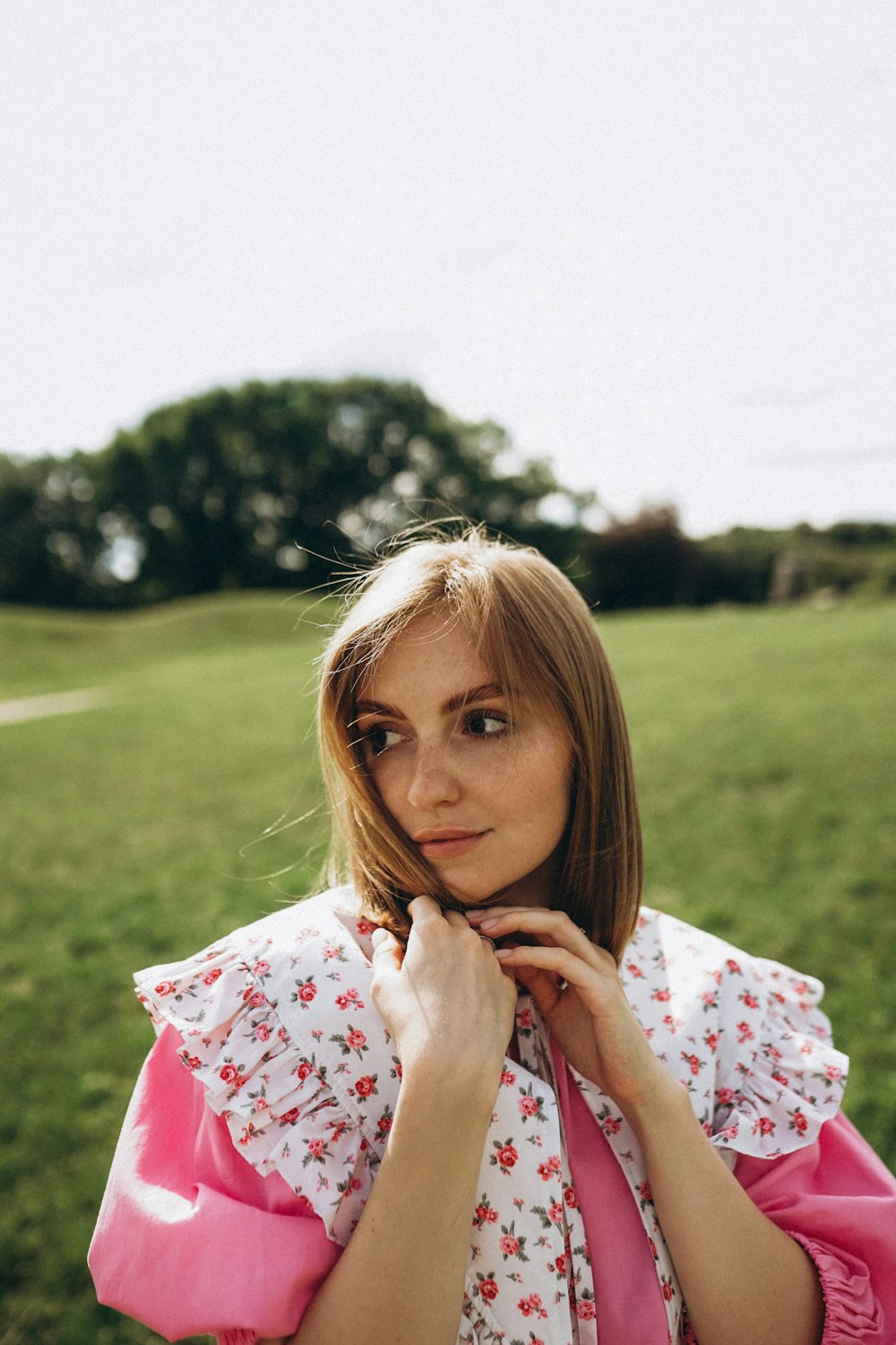 a woman standing in a field with her hands on her chin