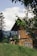 A cozy wooden house surrounded by lush greenery on a sunny day.