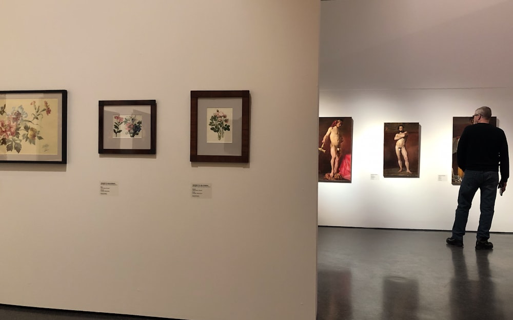 a man standing in front of a wall with paintings on it