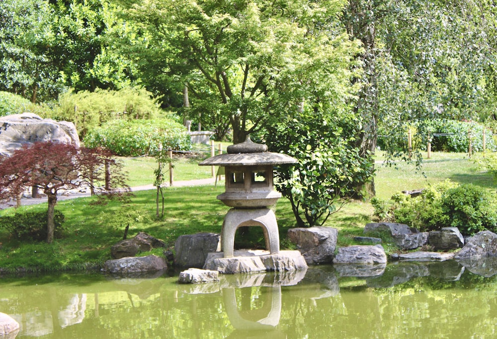 a pond with rocks and a stone lantern in it