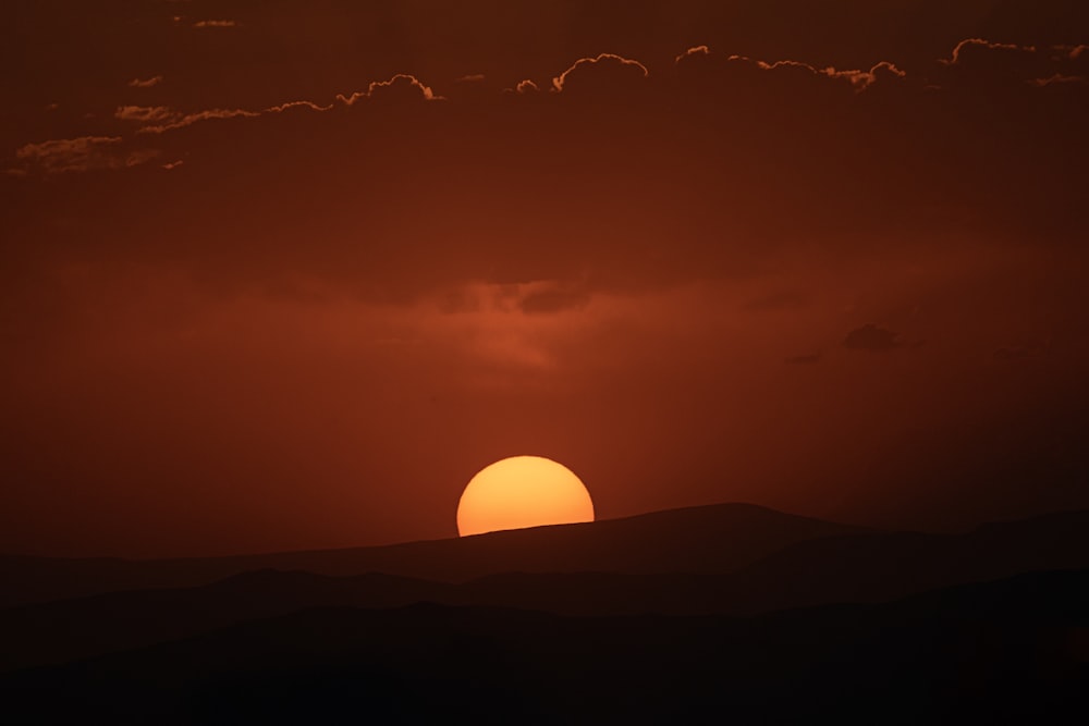 the sun is setting over the mountains in the distance