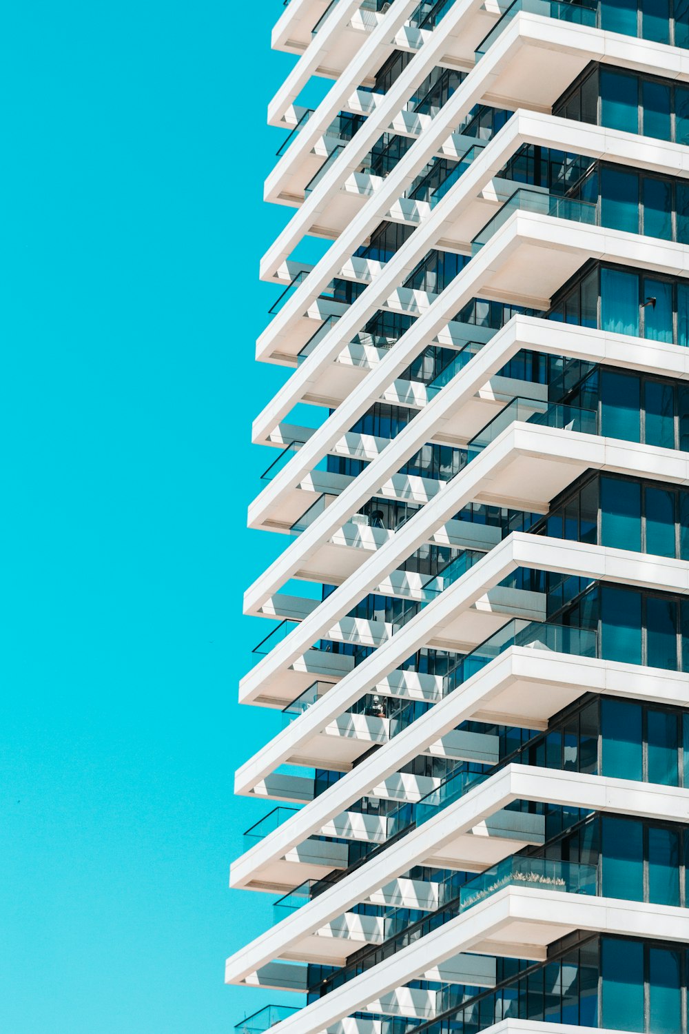 a tall white building with balconies against a blue sky