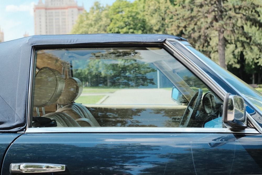 a blue car parked in a parking lot with trees in the background