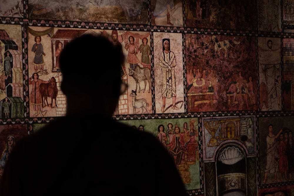 a man standing in front of a wall with paintings on it