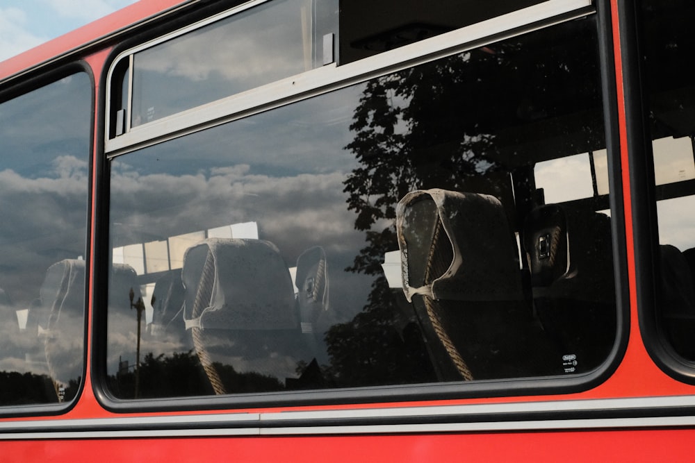 a red double decker bus with its reflection in the windows