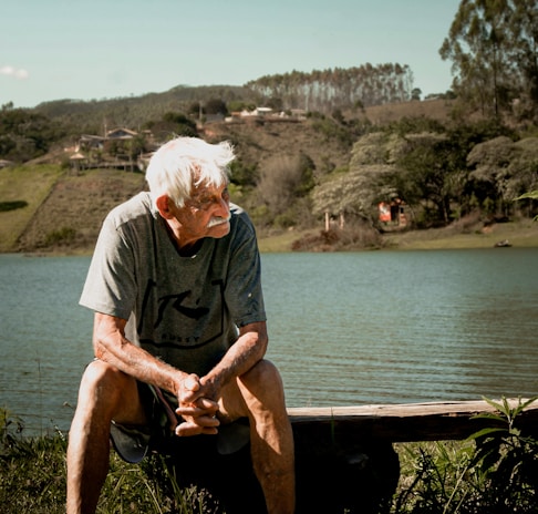 An elderly man sitting on a park bench, reflecting on life with a thoughtful expression.