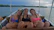 Friends laughing together aboard a boat, with water splashing around them.