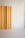 A minimalist interior featuring a vertical wooden panel against a smooth, light-colored backdrop. The panel displays a natural wood grain pattern and is positioned to one side, creating a subtle contrast with the plain surroundings.