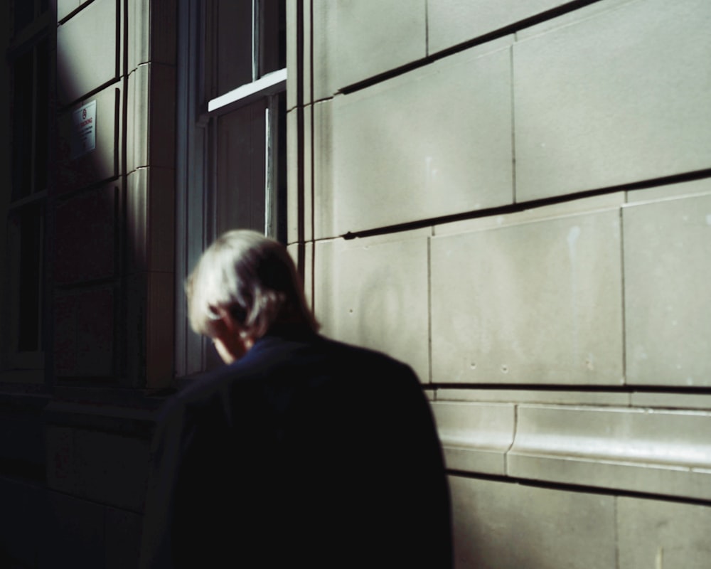 a man standing in front of a window talking on a cell phone