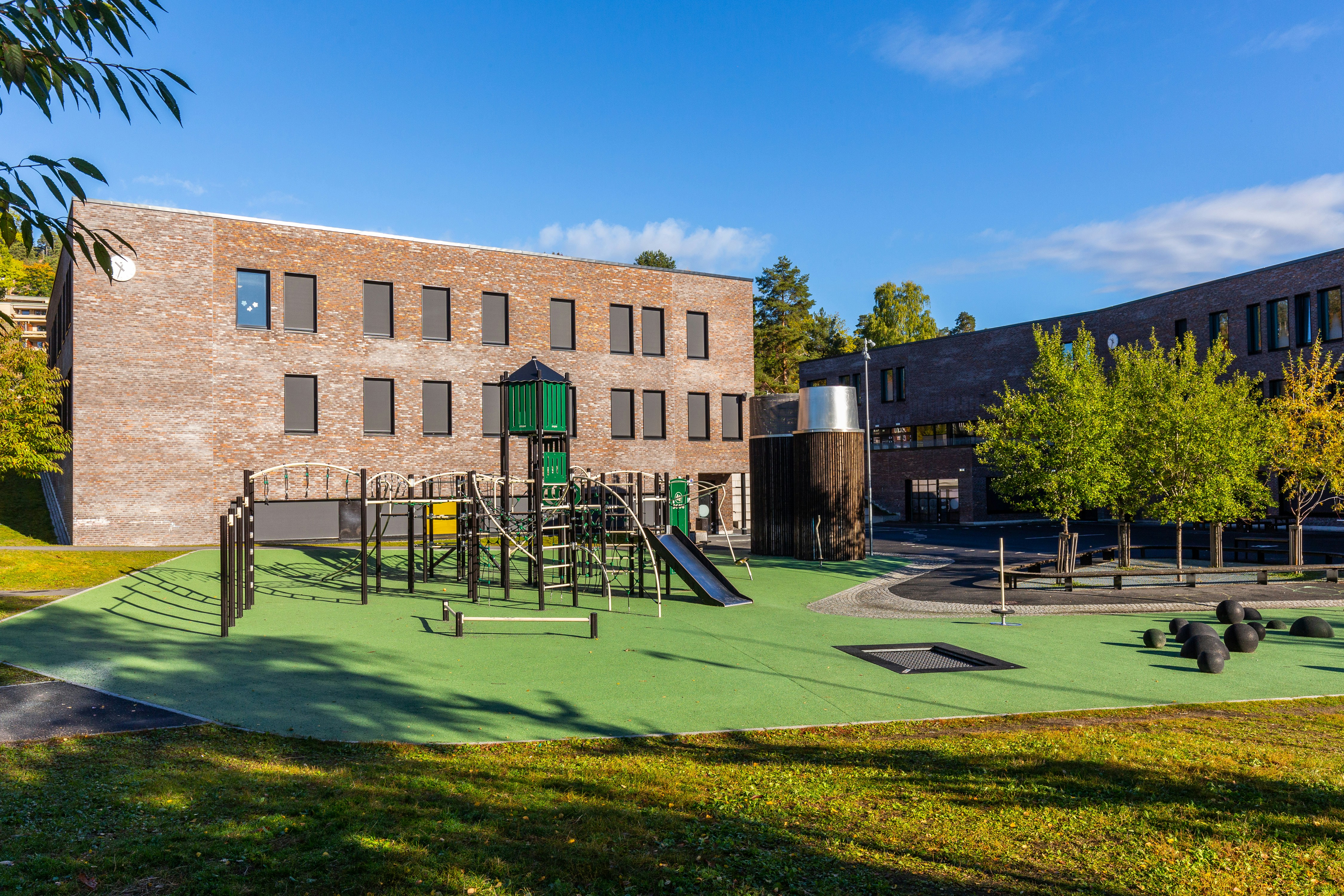 Modern school building exterior with clear blue sky, well-maintained campus grounds, educational architecture