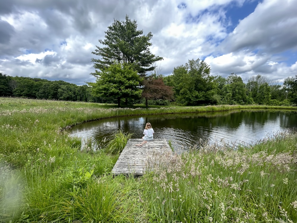 a person sitting on a dock near a body of water