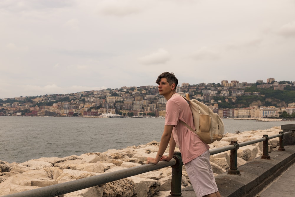 a man standing on a railing next to a body of water