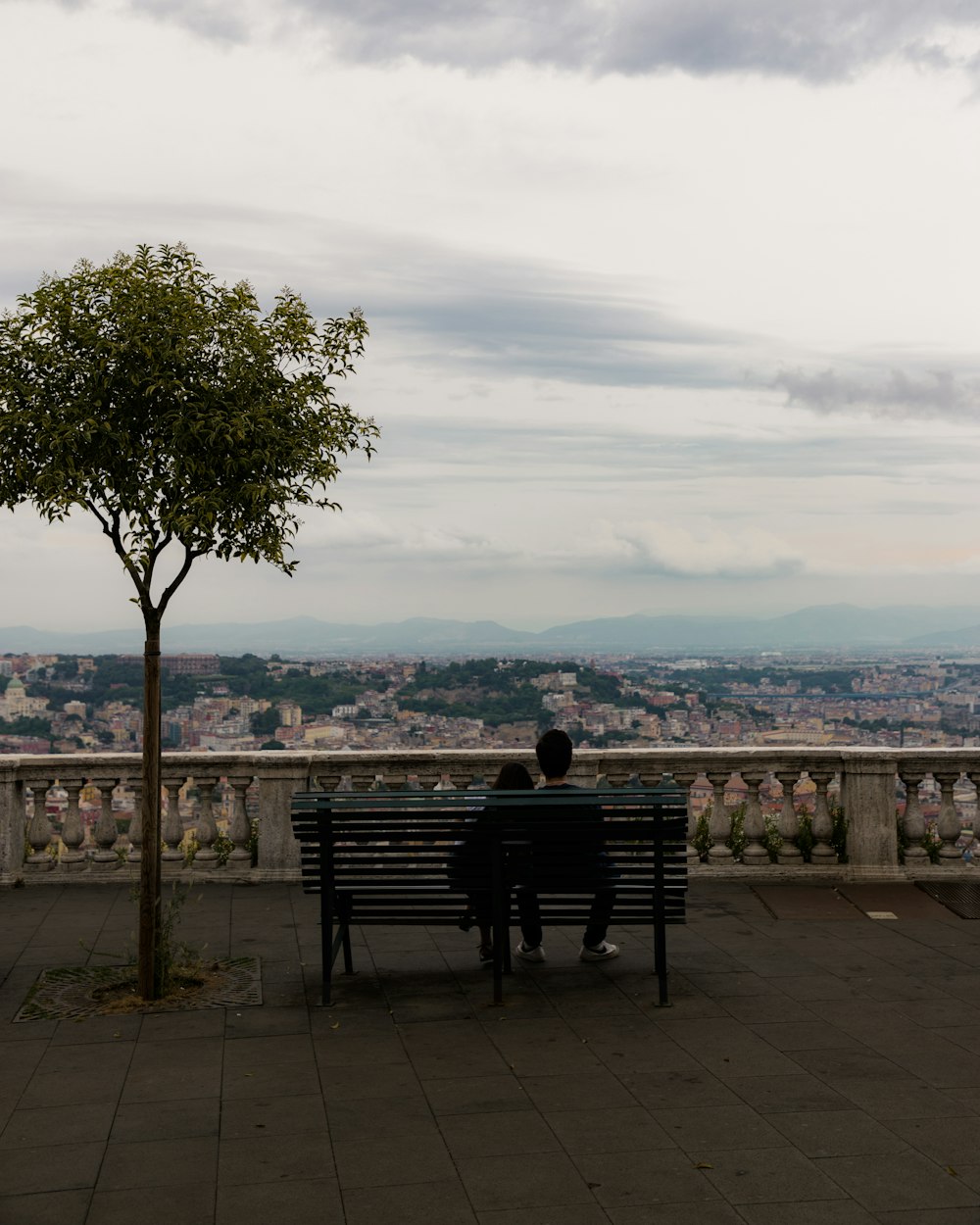 Un homme assis sur un banc regardant une ville