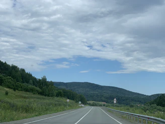 A freshly paved highway stretching through lush green landscapes under a clear blue sky.