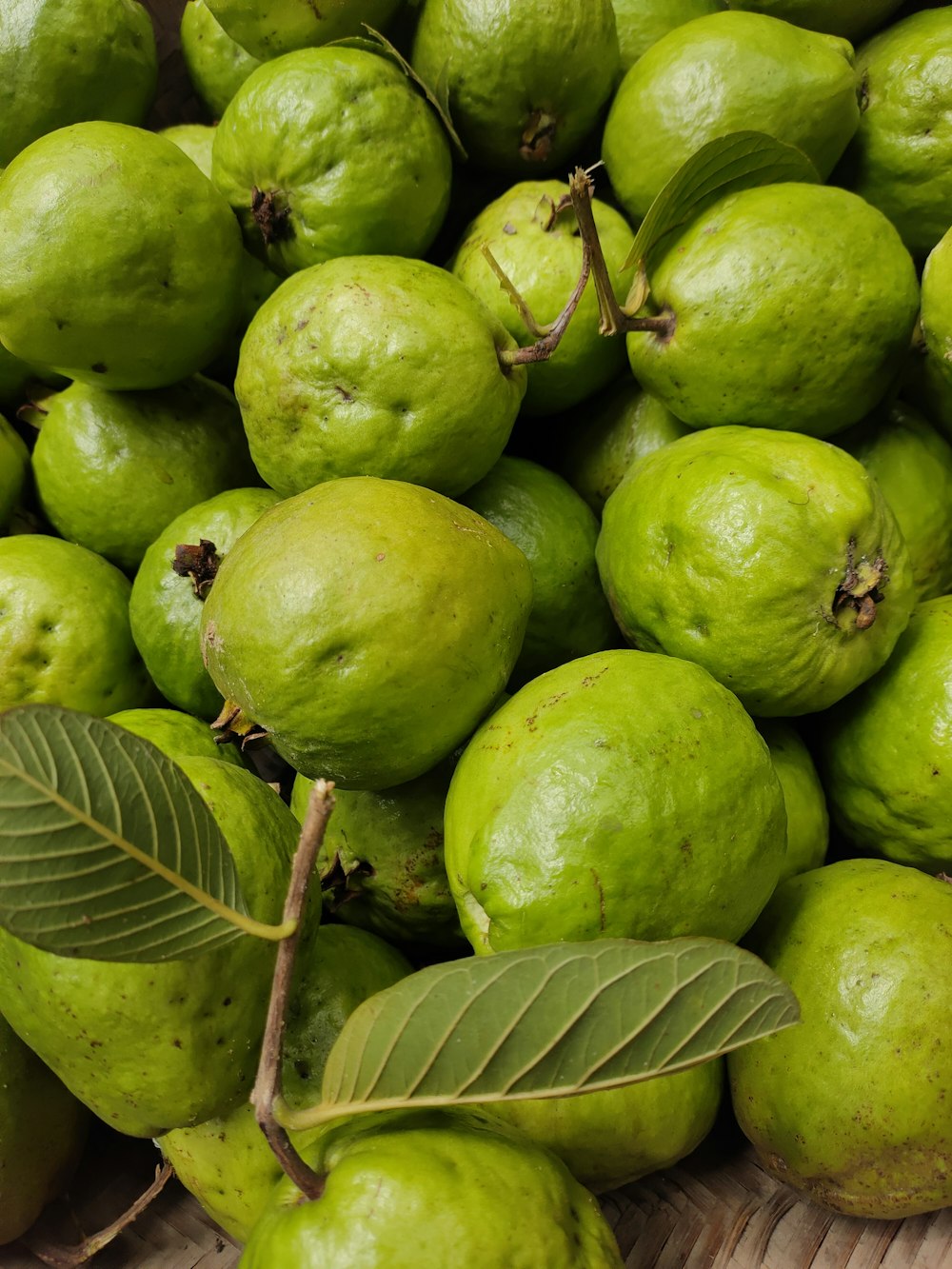 a pile of green fruit sitting on top of a wooden table