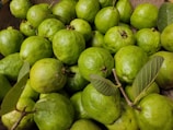 a basket full of limes with green leaves