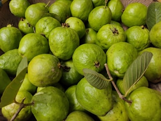 a basket full of limes with green leaves