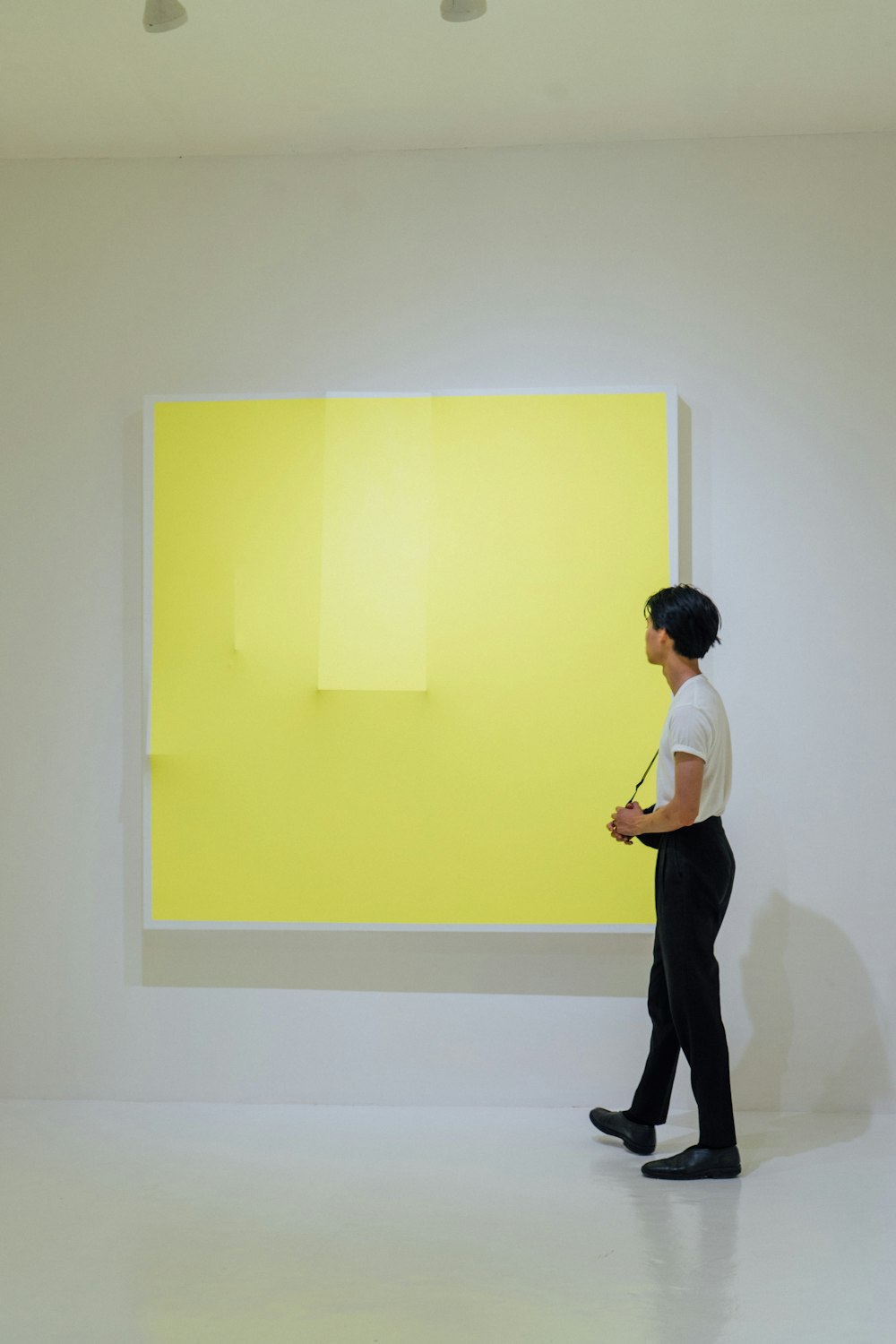 a person standing in front of a yellow painting