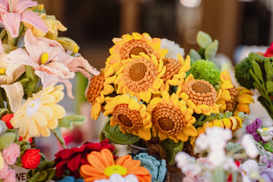 A collection of intricately crocheted flowers, including sunflowers and other varieties, arranged in a vibrant and colorful display.