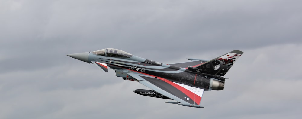 a fighter jet flying through a cloudy sky