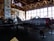 A vintage aircraft is displayed inside a dimly lit hangar with wooden beams. The aircraft, marked with the number 23 and a red star, is metallic with red accents. Large windows line the wall in the background, allowing some light to filter in. Posters and other aircraft-related displays are visible around the hangar.