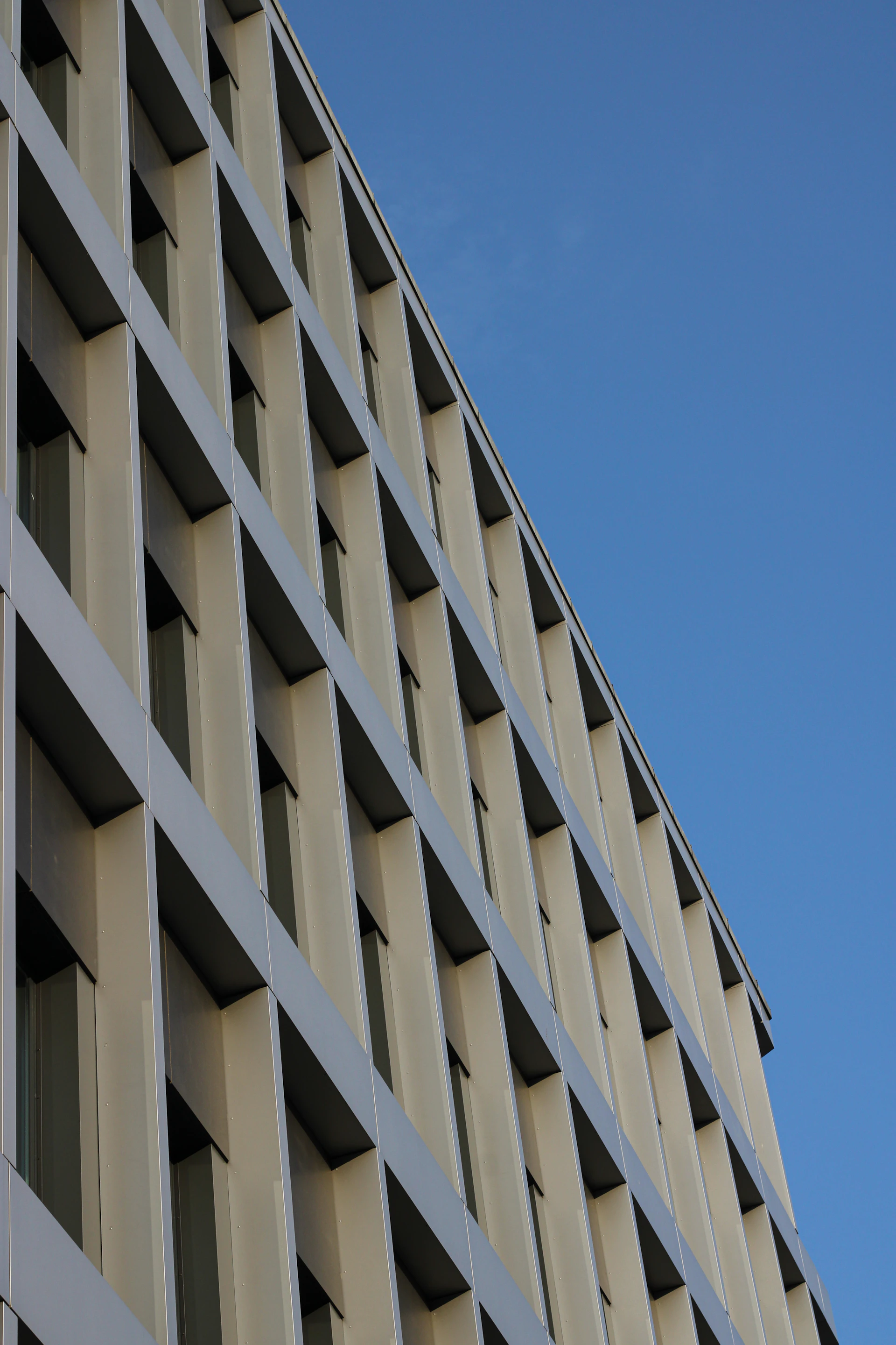 Wide-angle view of an elegant urban building facade emphasizing simplicity and architectural harmony against a clear sky.