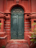 Architectural detail of a deep olive green door framed by volcanic stone walls, capturing the blend of tradition and modernity.