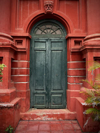 Architectural detail of a deep olive green door framed by volcanic stone walls, capturing the blend of tradition and modernity.