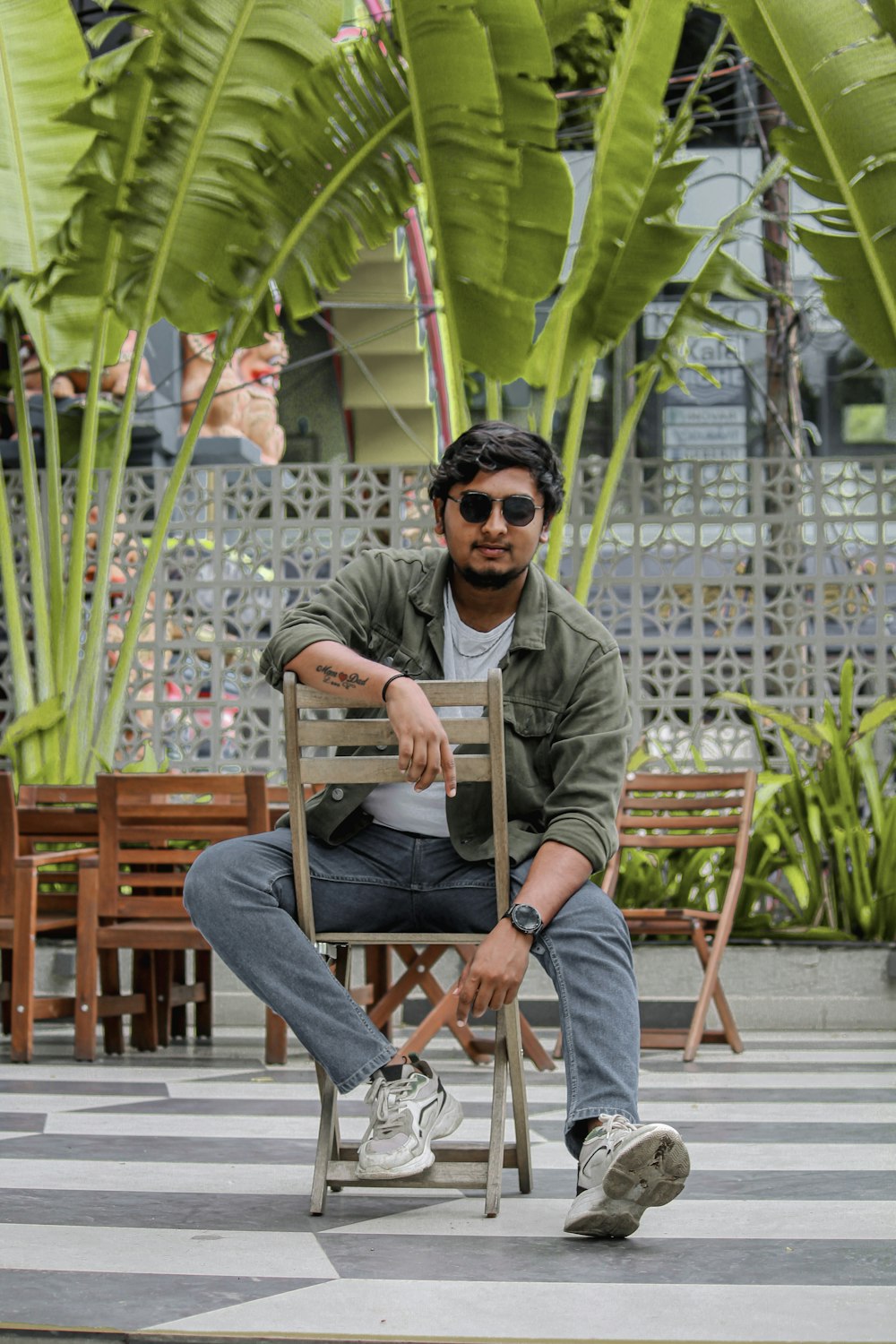 a man sitting on a chair in front of a palm tree