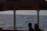 A group of tourists on a boat watching a whale breach the ocean surface.