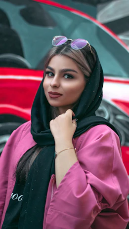 A young woman posing confidently in a trendy Pakistani outfit against a cultural mural.