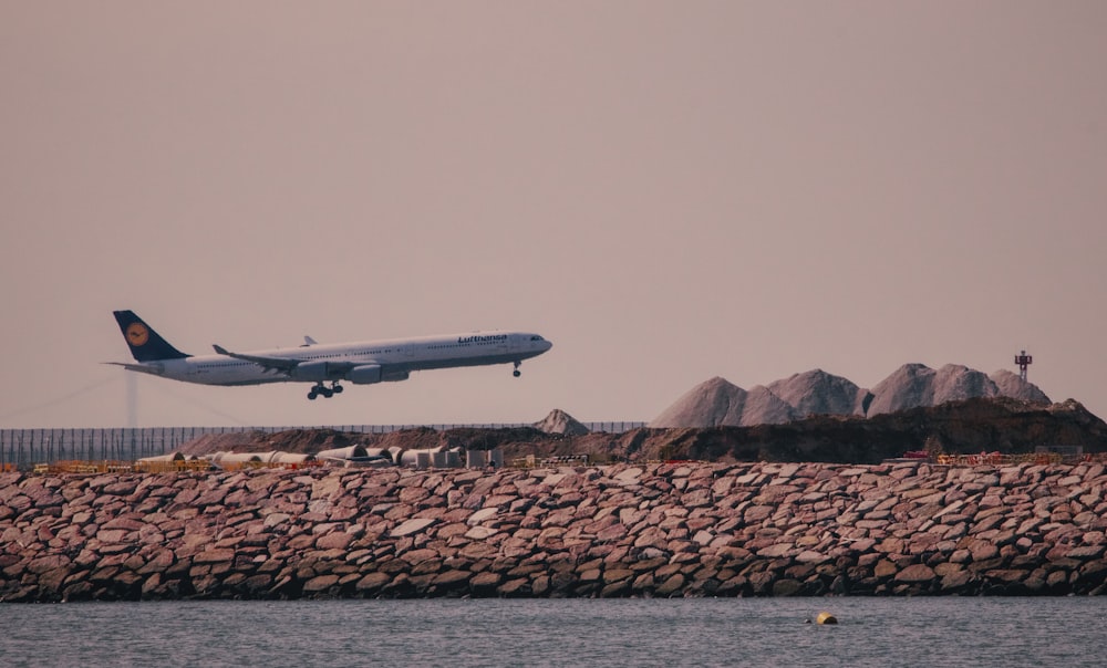 a large jetliner flying over a body of water