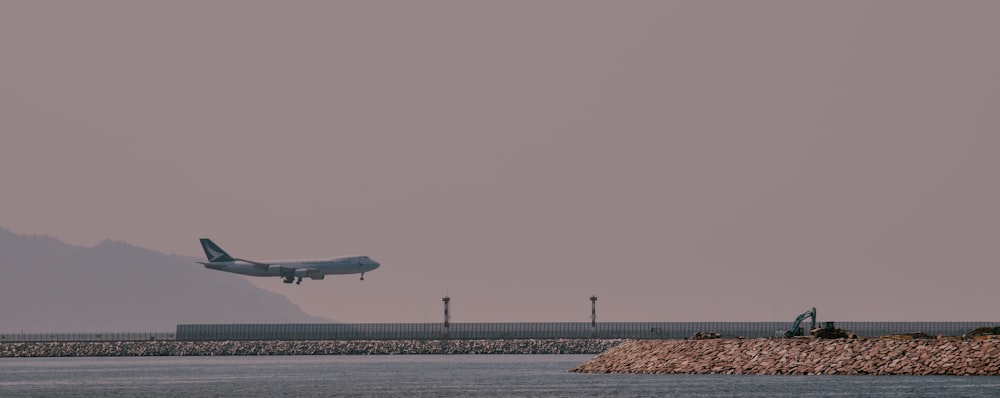 a large jetliner flying over a body of water