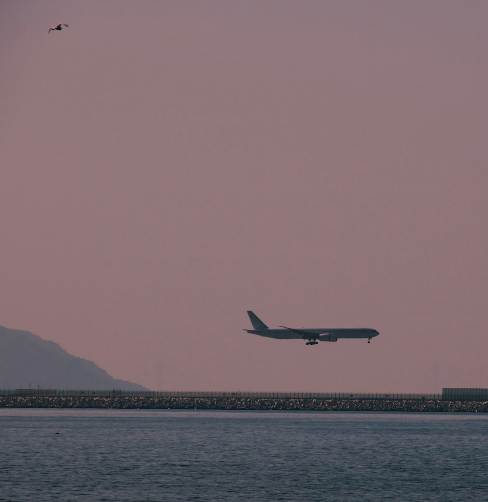 a large jetliner flying over a large body of water