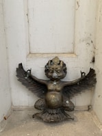 A beautifully aged bronze antique figurine displayed on a shelf.