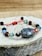 Close-up of a handmade macramé bracelet with colorful crystals on a wooden table.