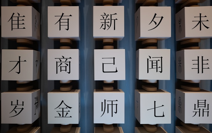 Several large white cubes with black Chinese characters are arranged in vertical columns against a blue background.