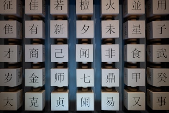 A series of rotating cubical panels each featuring a single Chinese character. The cubes are aligned in columns and have a mechanical appearance with visible axles or connectors. The background is a soft blue-gray color, providing contrast to the black characters on the light-colored cubes.