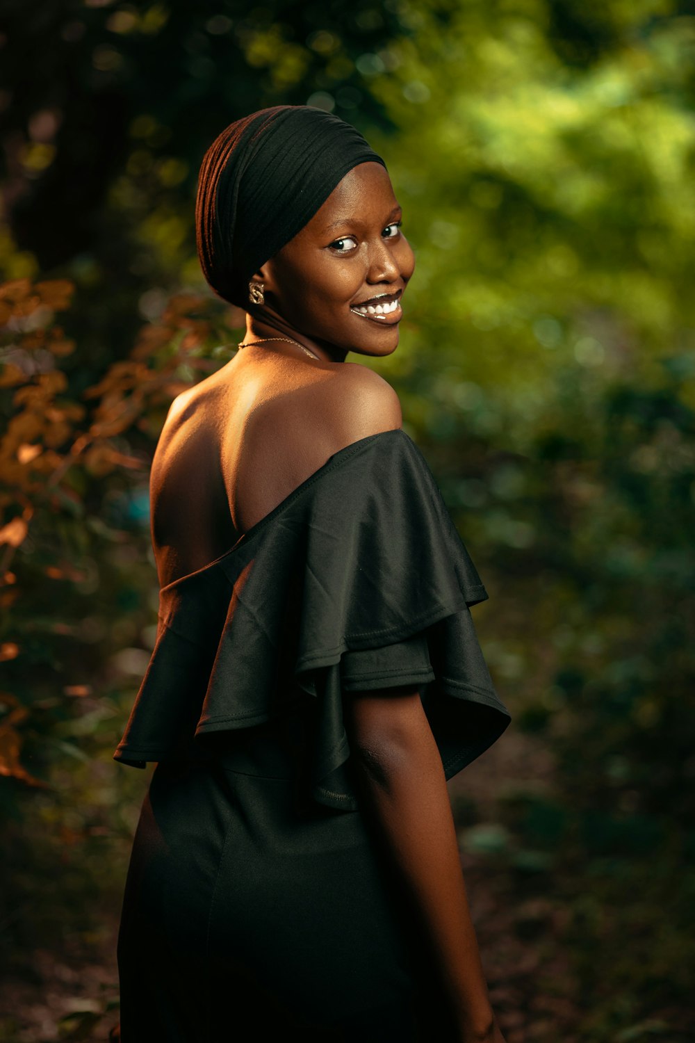 a woman in a black dress standing in the woods