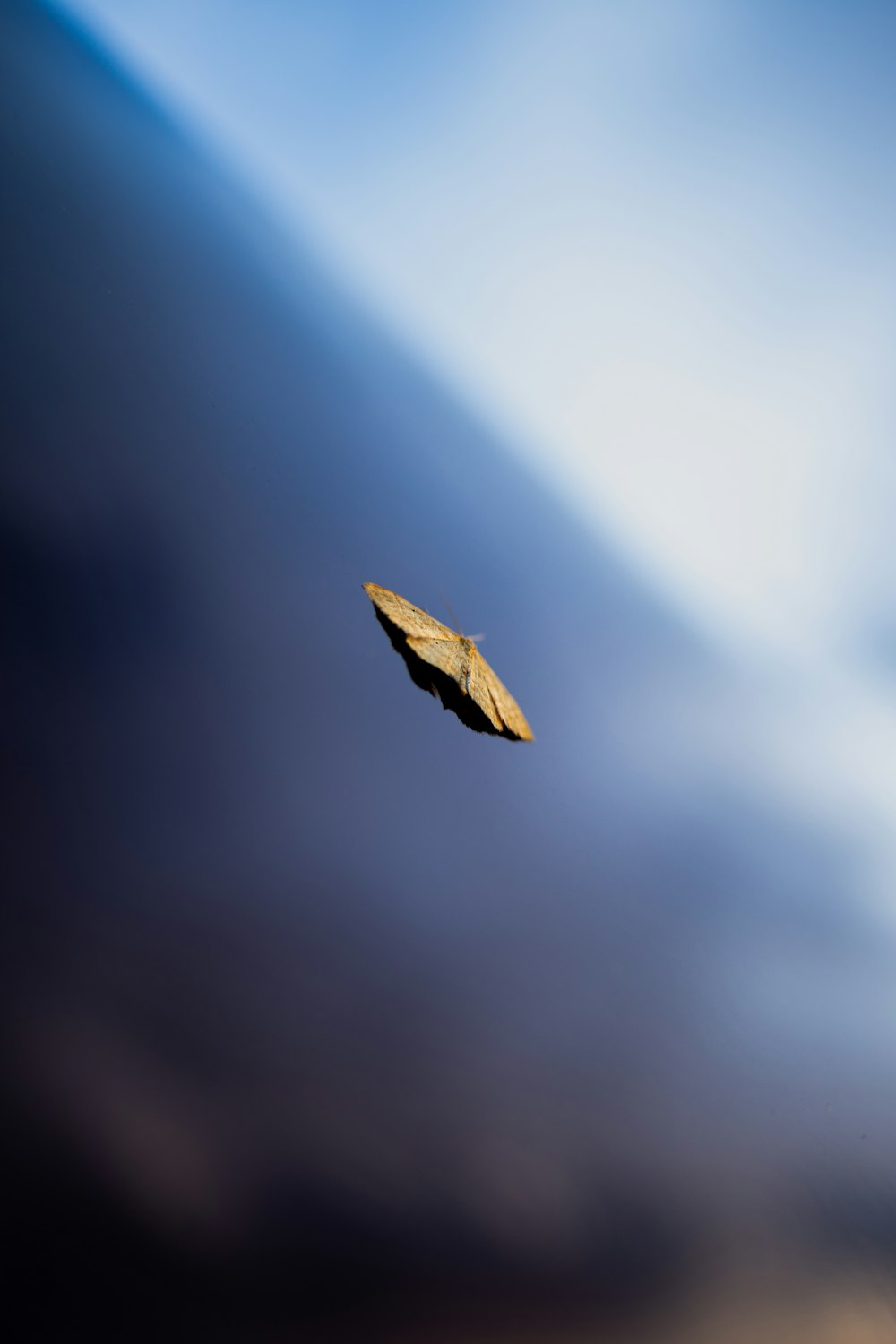 a yellow kite flying through a cloudy blue sky